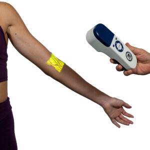 Arm extended to the side with a neon yellow adhesive patch on the forearm being scanned by a handheld therapy device