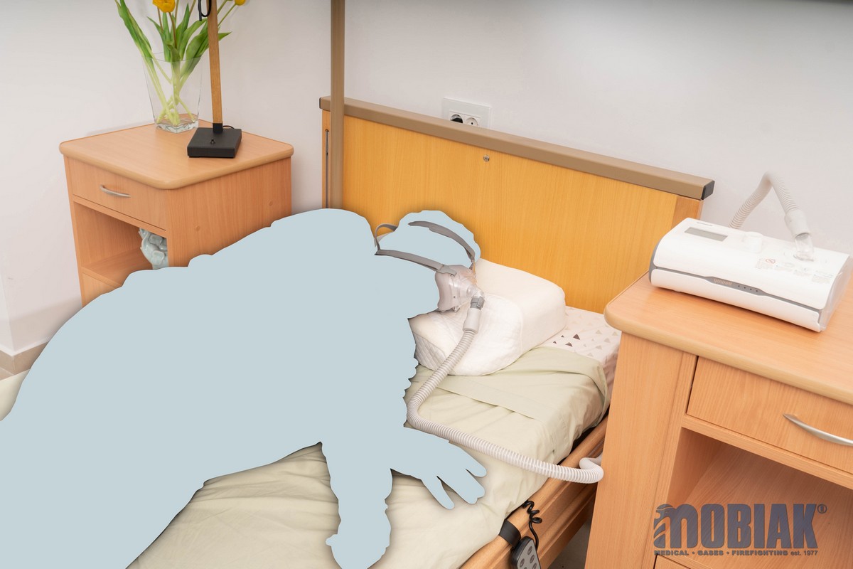 Silhouetted patient on a hospital bed with a breathing mask connected to a machine.