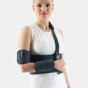 Woman wearing a blue arm and elbow immobilizer with forearm and upper-arm supports secured by straps on a white top.