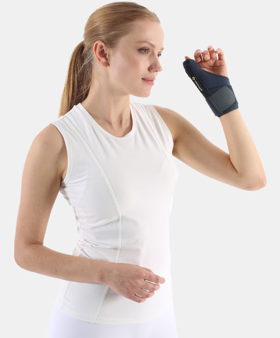 Woman in a white sleeveless top adjusts a dark wrist brace on her right wrist for support.